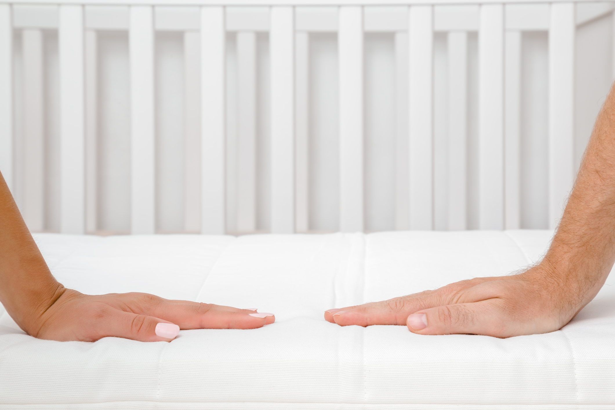 A man and a woman pressing down on a mattress 