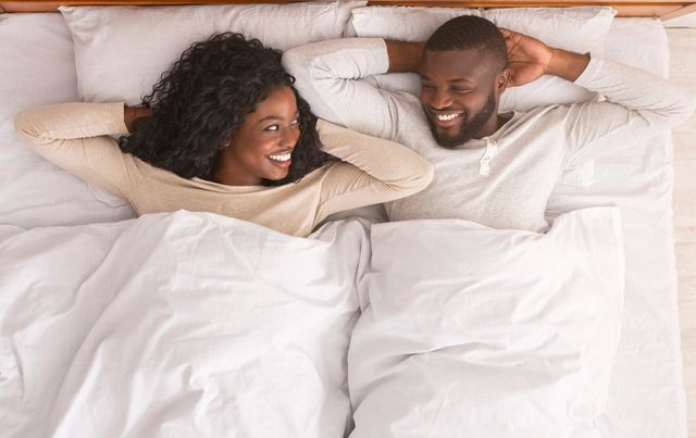 top view of a couple laying with their arms up and smiling on a mattress