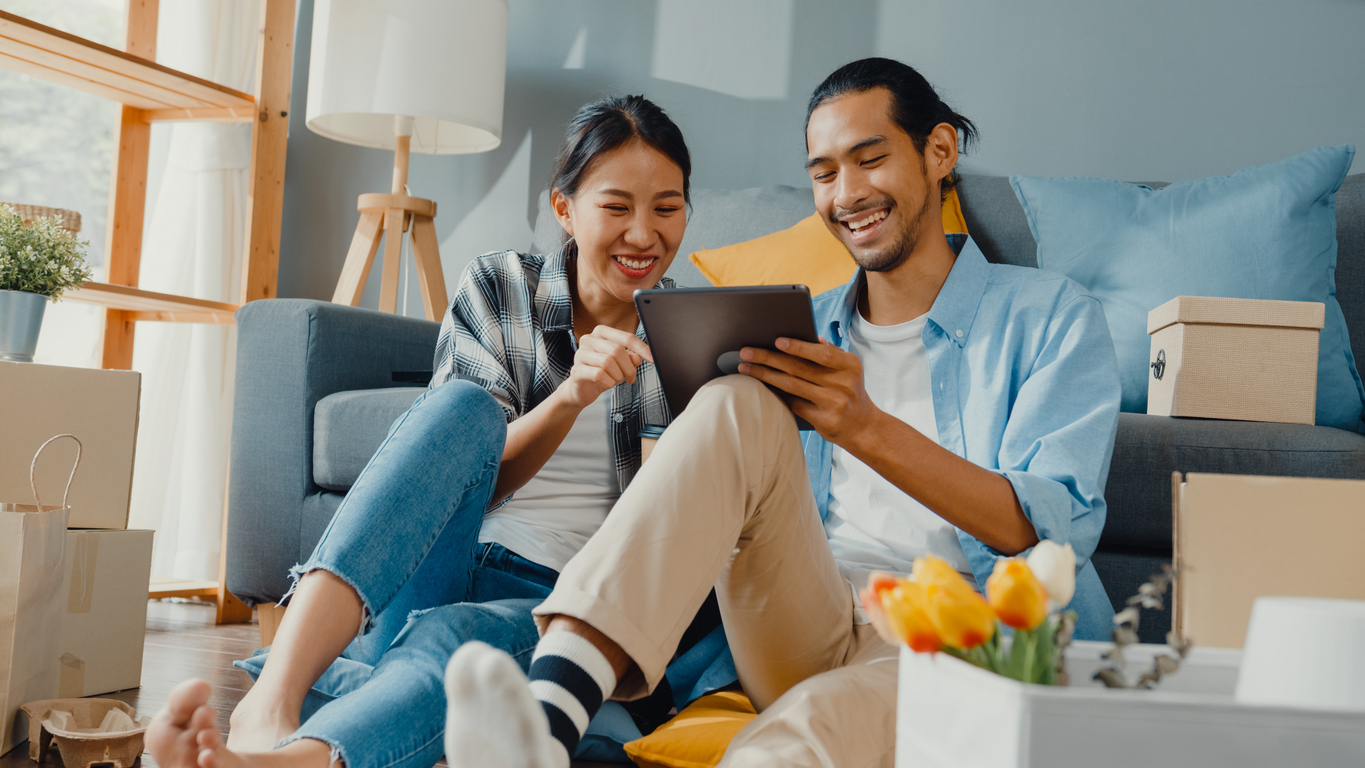 Happy young couple using a tablet to online shop for furniture. 