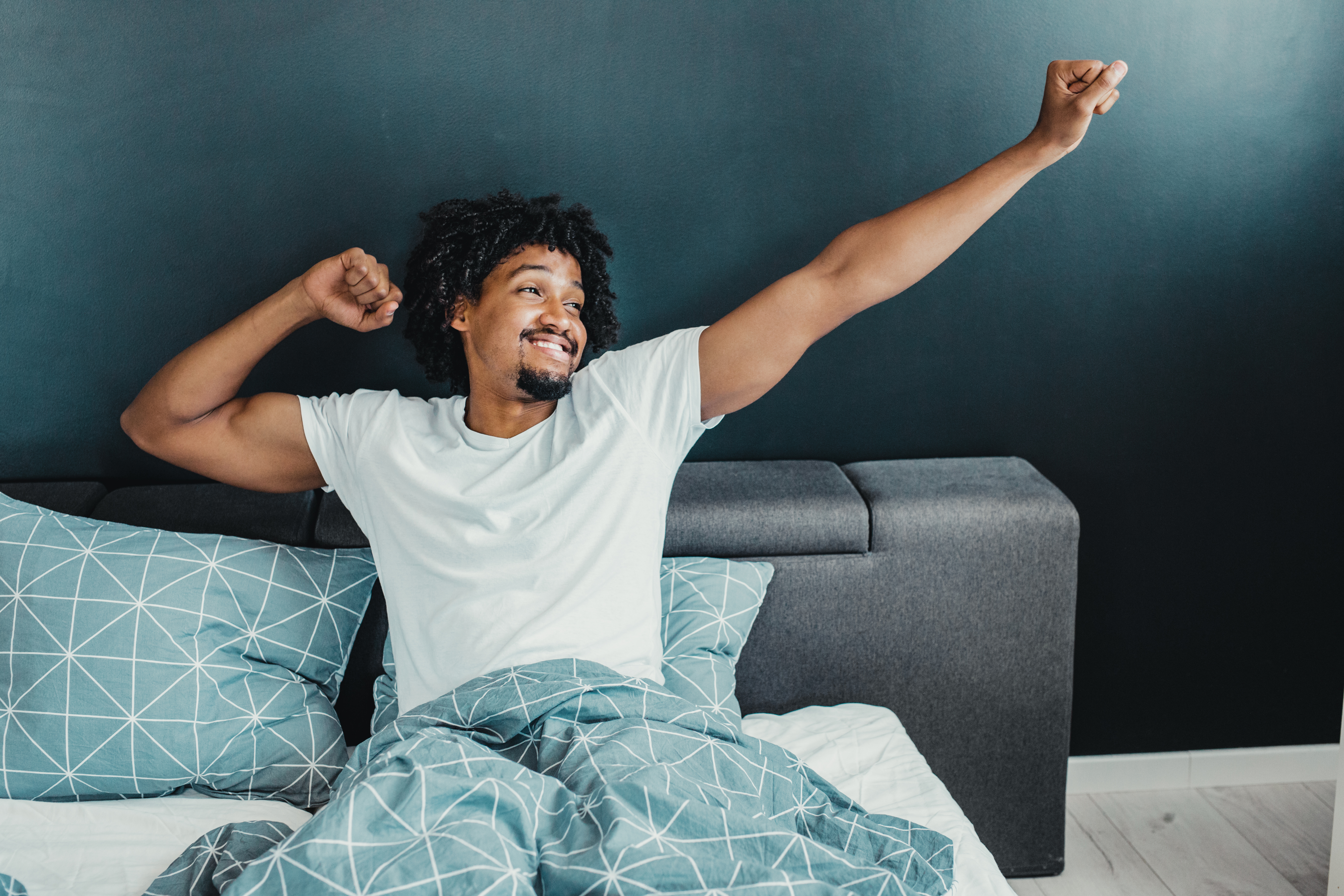 Young man  stretching and smiling in bed 
