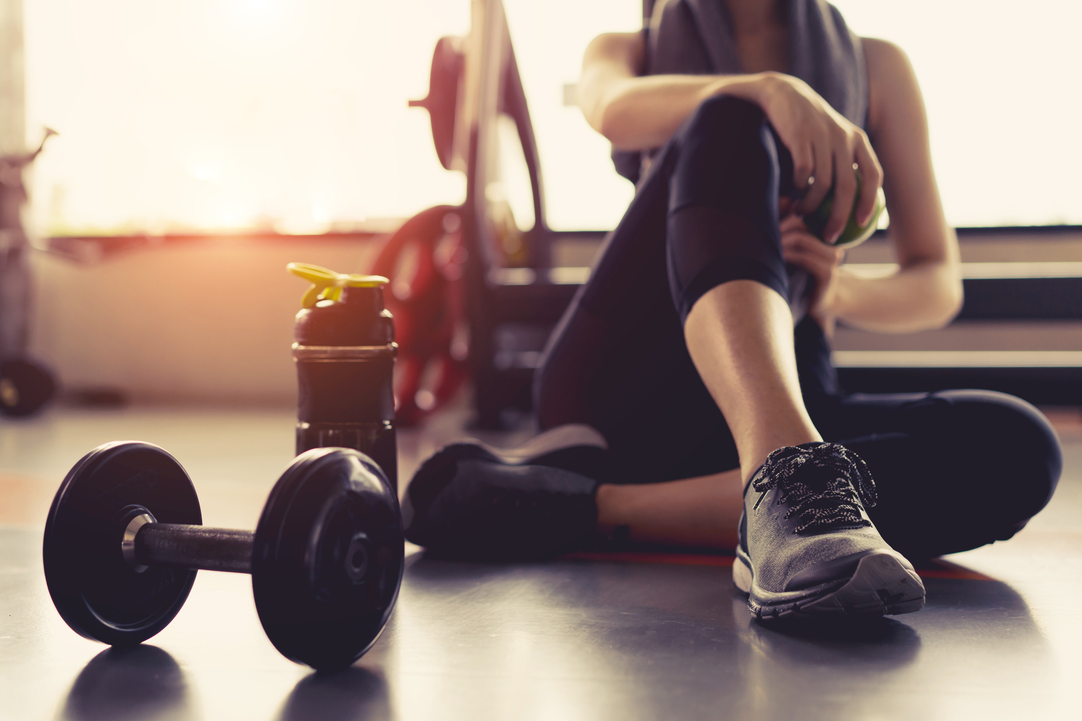 sitting on the gym floor with a dumbbell and bottle of water