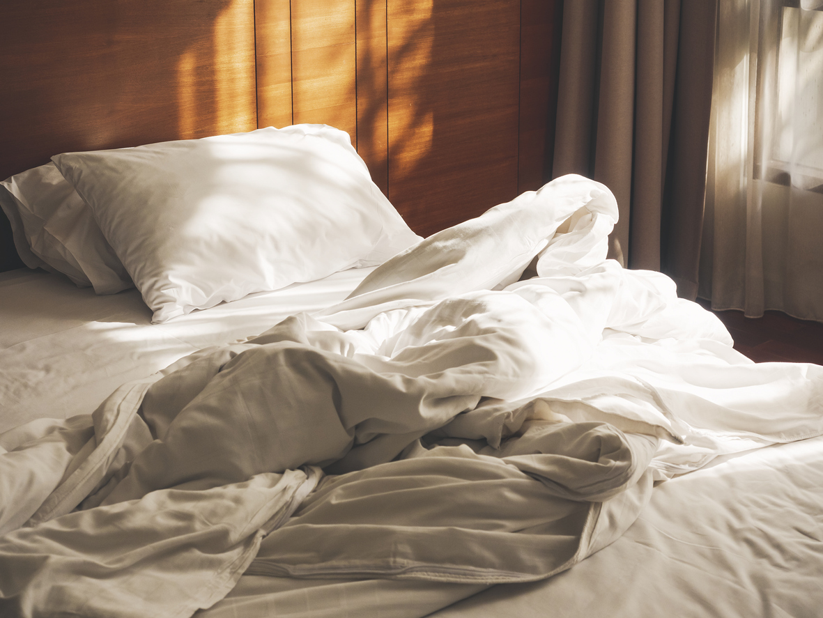 unmade bed with morning sunlight