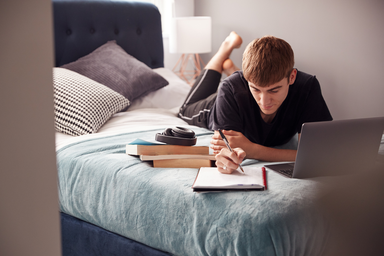 Man completes his homework in bed