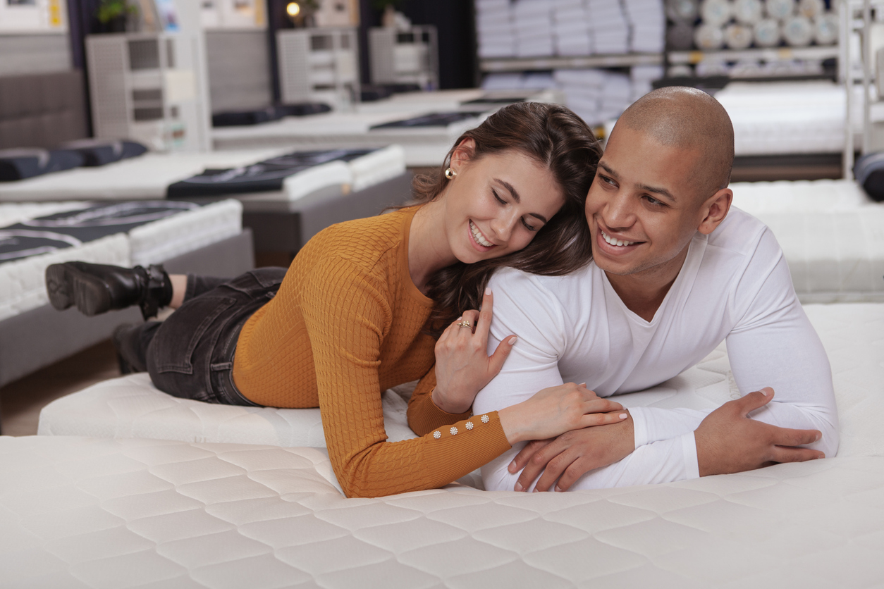 couple laughing, enjoying shopping together for a new bed