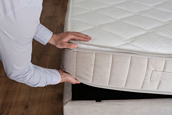 A person inserting a mattress into a bed frame 
