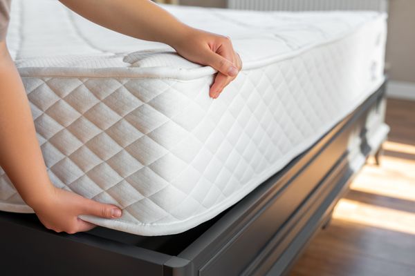 A person inserting a mattress into a bed frame