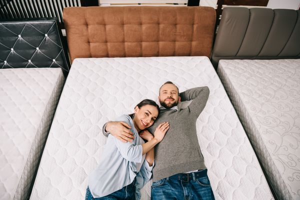 A man and a woman testing out a mattress in a store