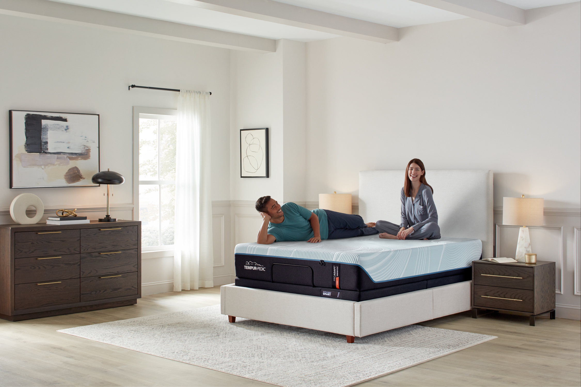 A couple laughing while sitting on top of a Tempur-Pedic mattress 