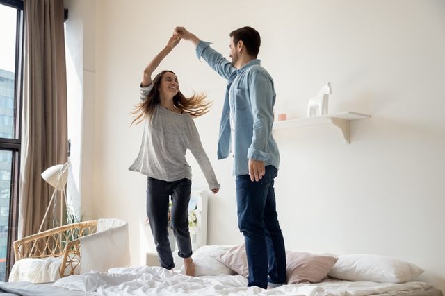 Front view of a man and woman dancing on their bed