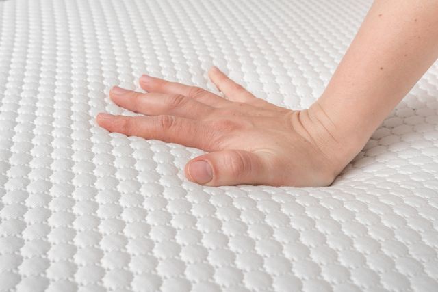 close view of a hand pressing on a foam mattress
