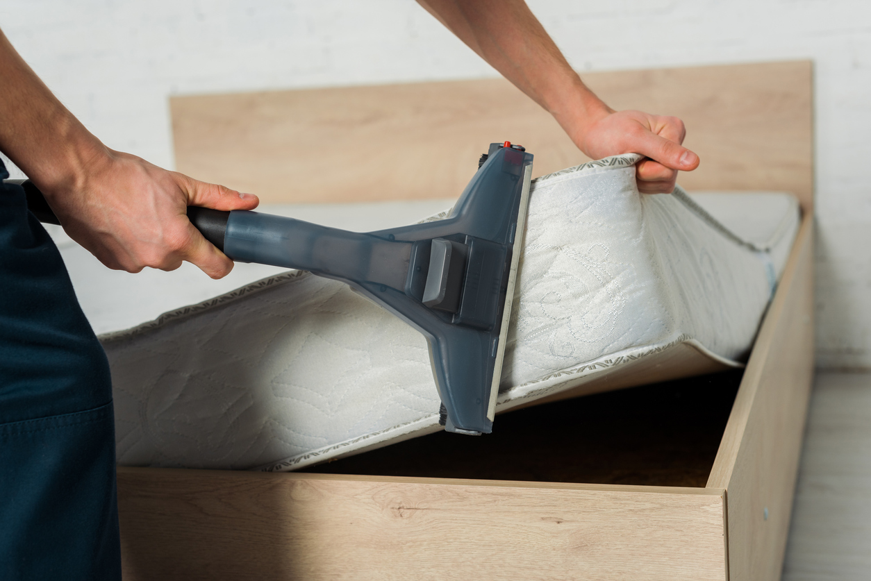 man removing dust on mattress with vacuum cleaner