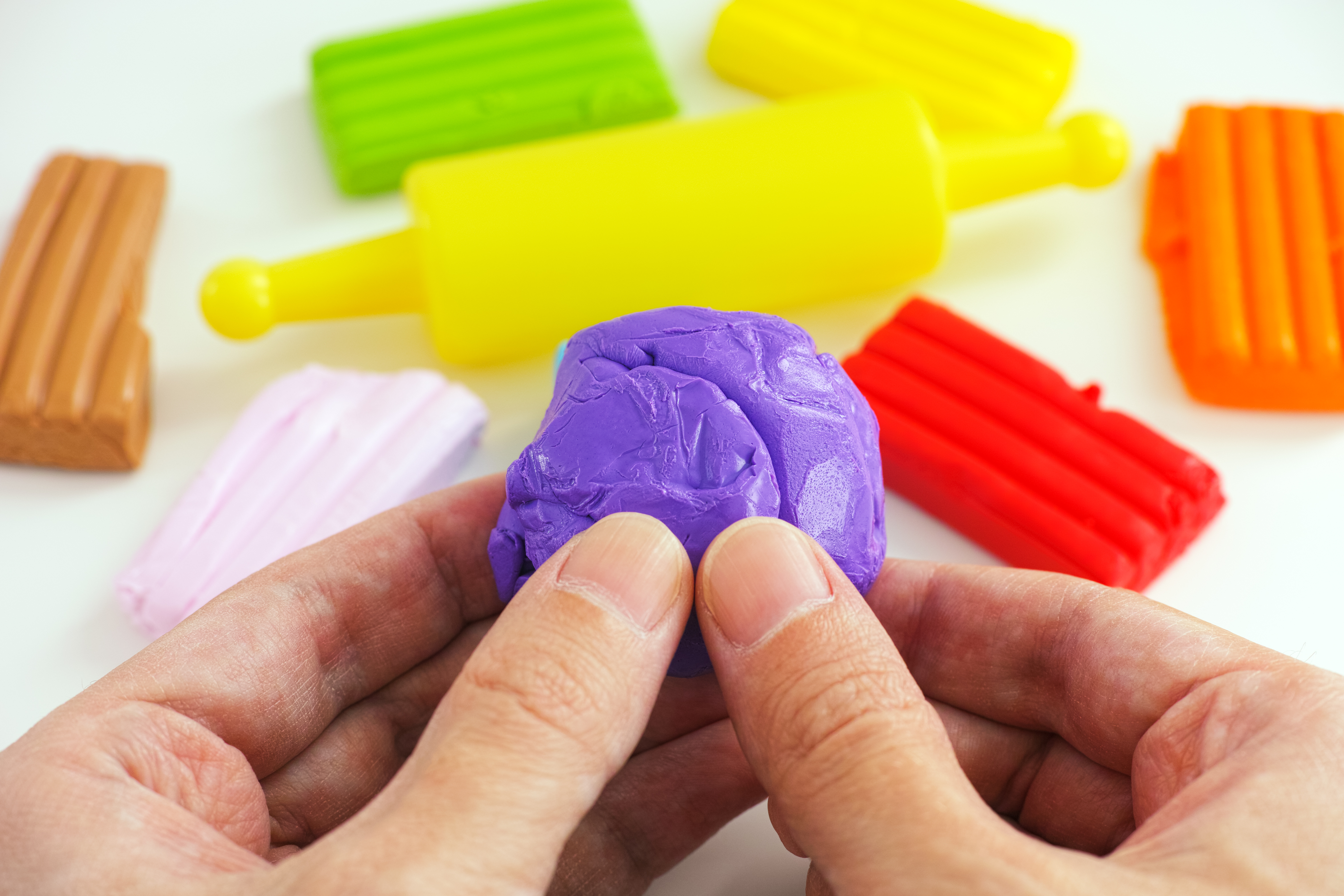 Person plays with several different colored clays