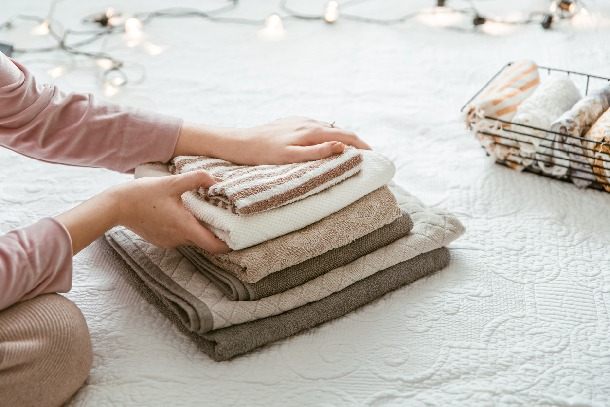 woman folding clean towels and clothes in bedroom