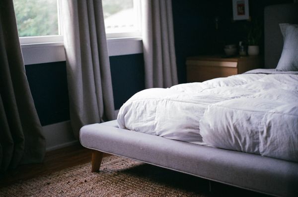 Platform bed with white comforter next to a window