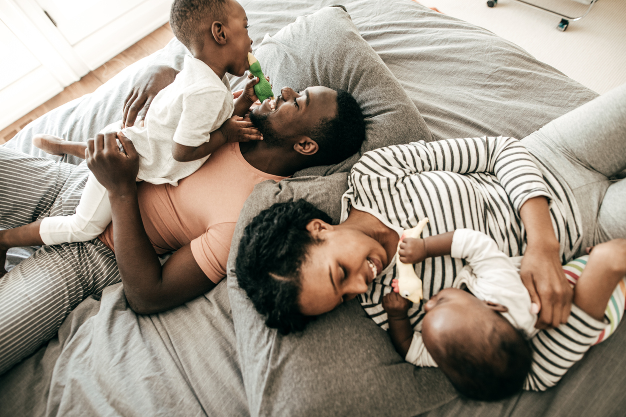 happy parents with two kids snuggling in bed