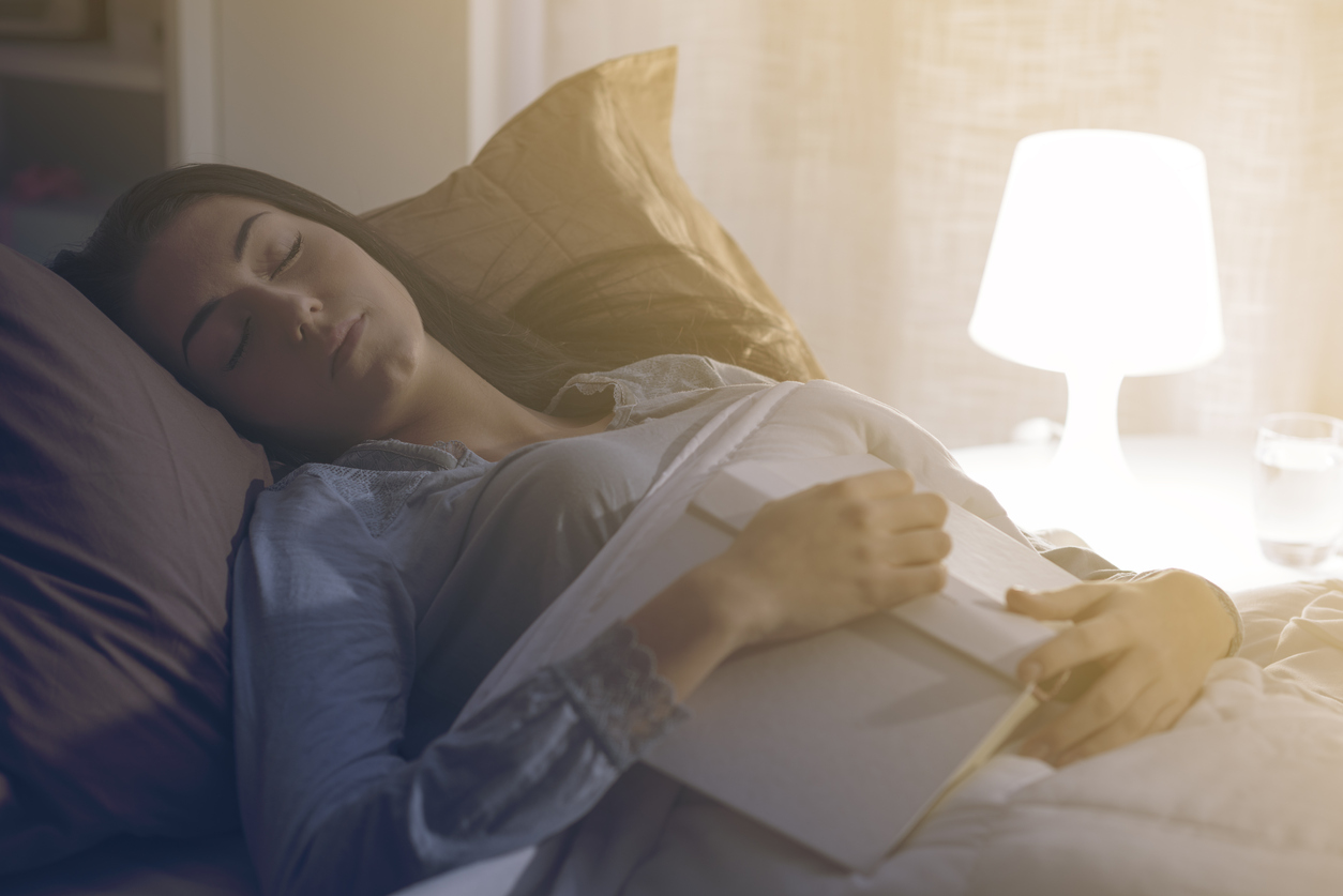 woman fallen asleep in bed while reading