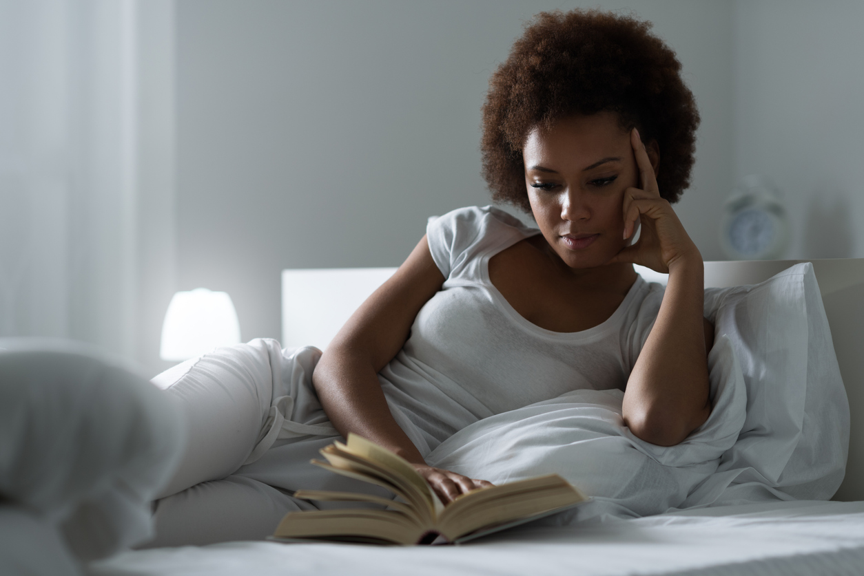 Young woman reading a book in bed