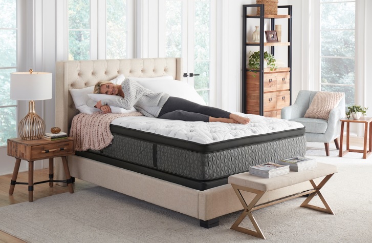 A woman happily curls up on her Scott Living mattress