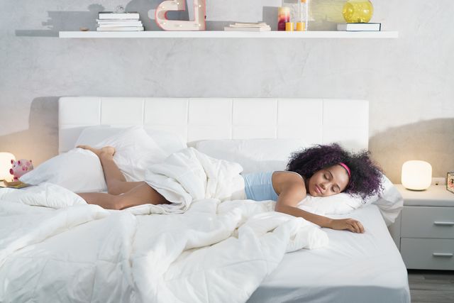 front view of a woman laying on her stomach sleeping on a mattress