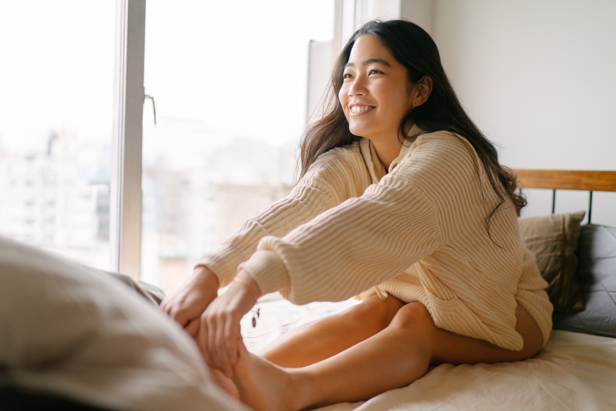 A young woman stretching and smiling in bed 