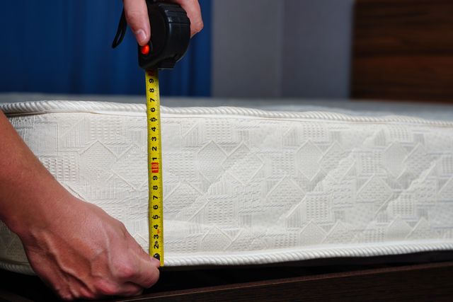 A person using a tape measure to measure a mattress 