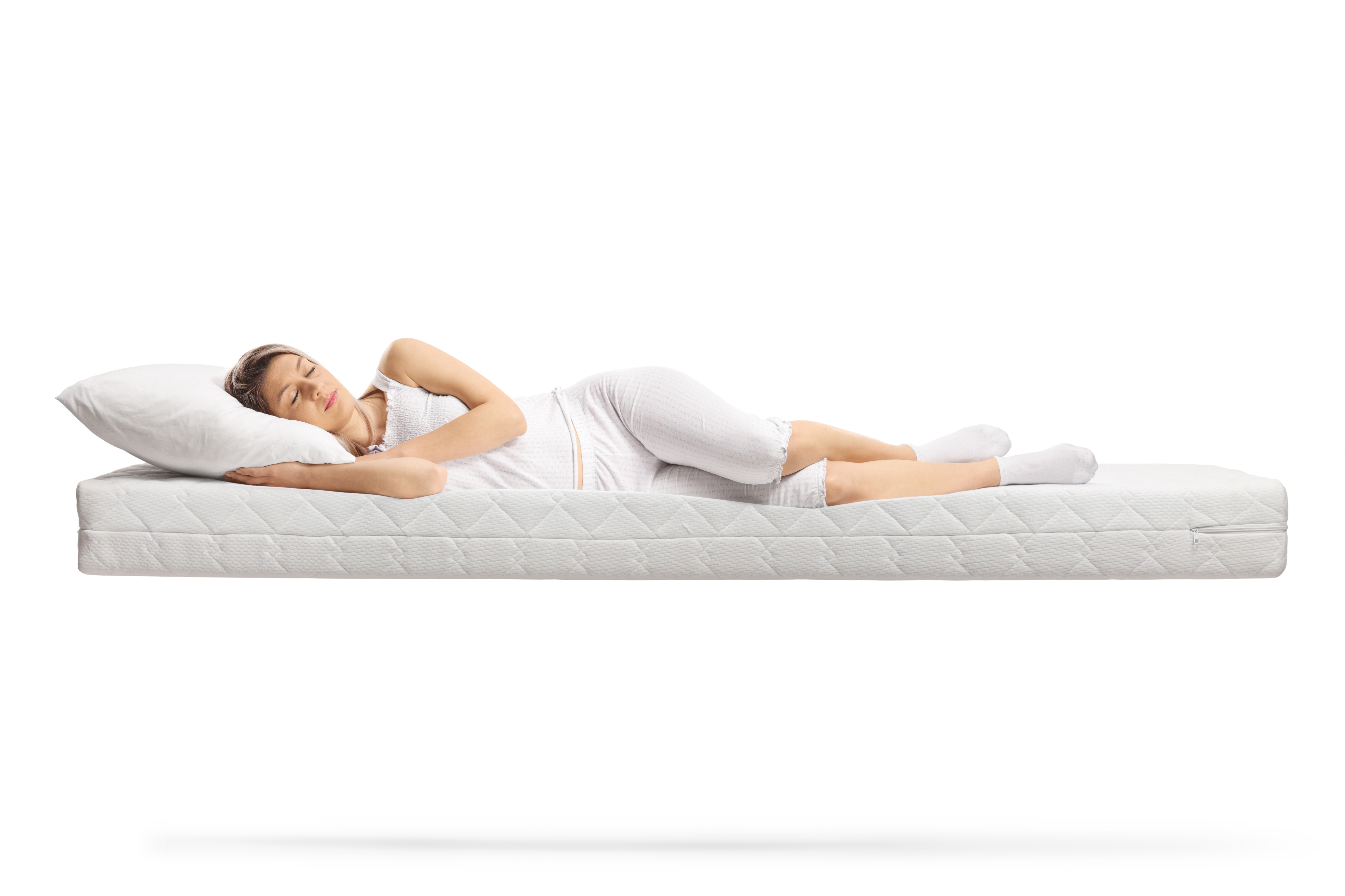 A woman sleeping on her side on a mattress 