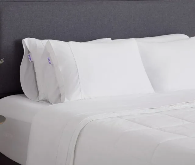 Purple pillows on a bed with white bedding 