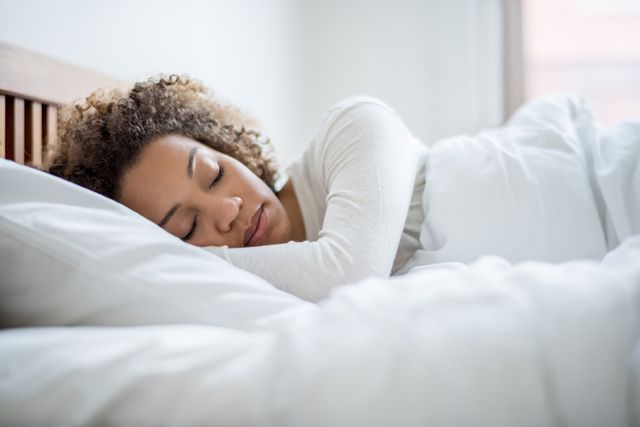 front view of a woman sleeping on her side in white bed