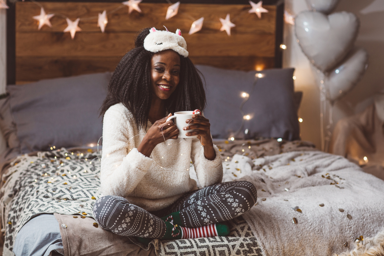 Woman sitting on her bed who’s just woken up from deep sleep with a sleep mask
