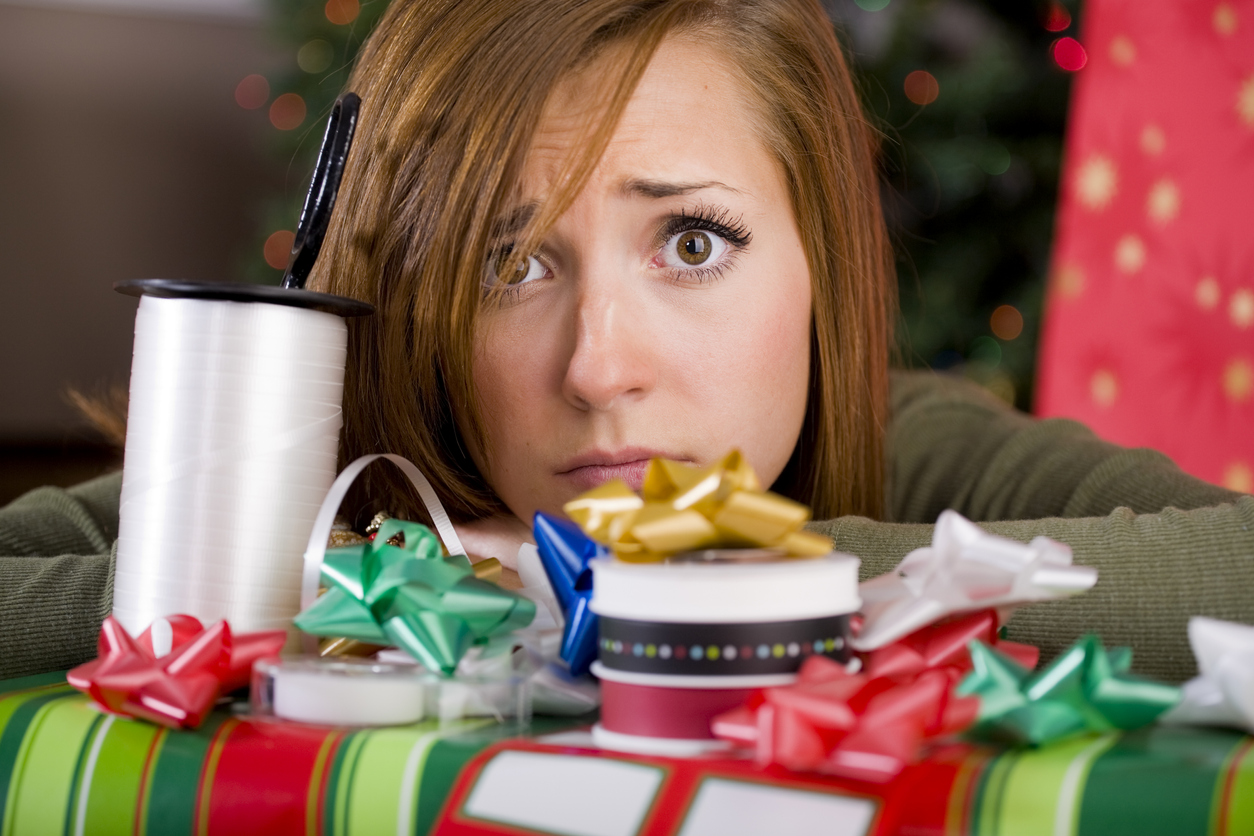 young woman wrapping Christmas presents in front of a Christmas tree