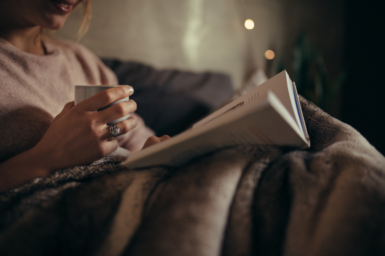 cropped shot of female hands with cook and coffee at night