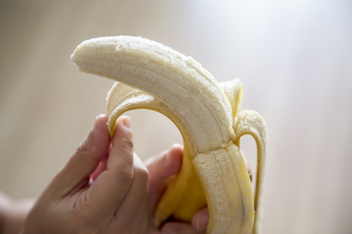 Hand peeling back a banana.