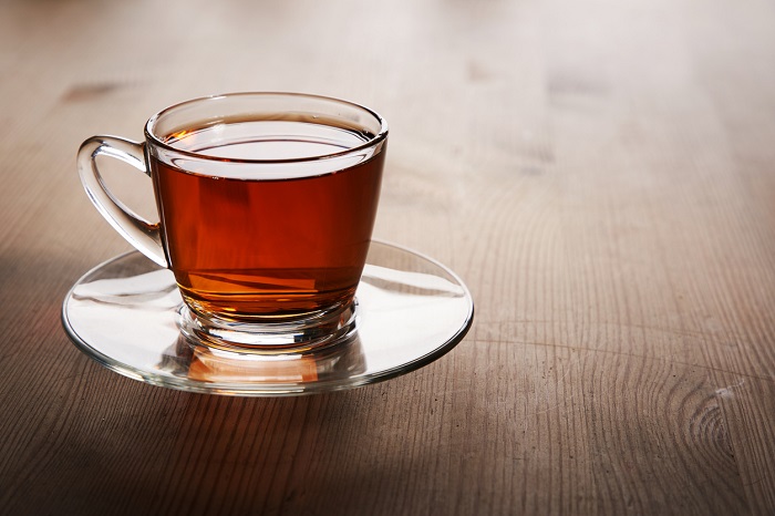Glass of hot tea on a glass plate.