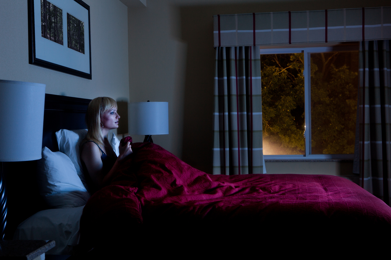 Woman watches TV in bed and is illuminated by screen light