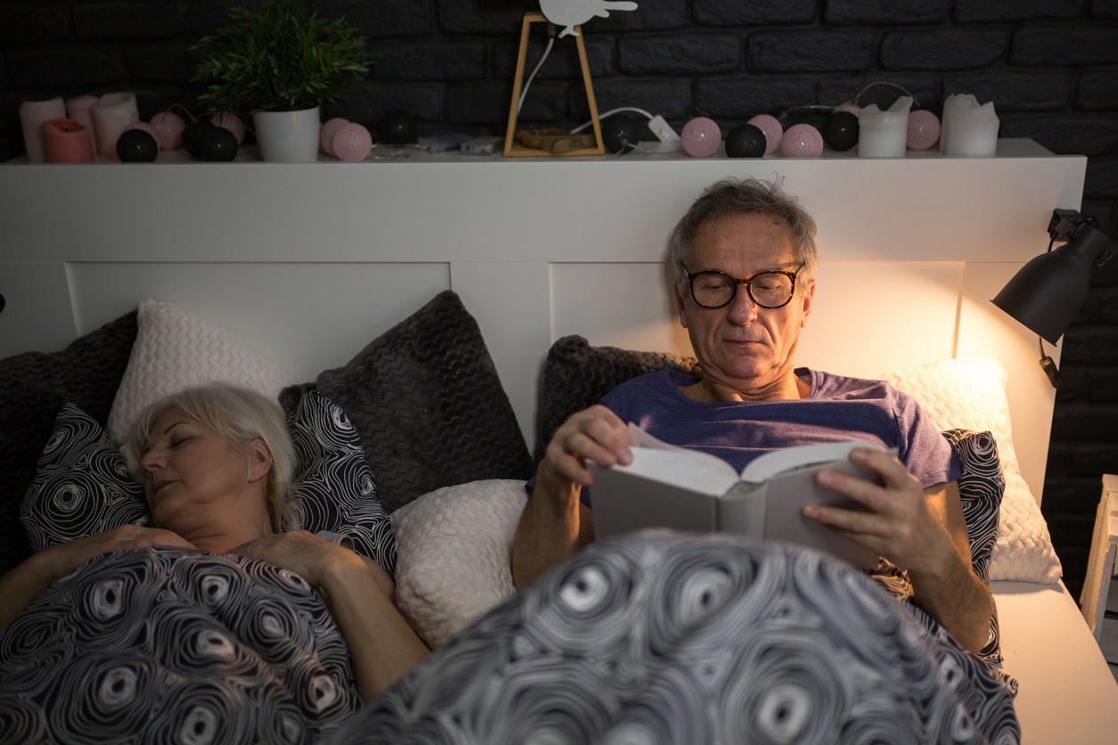 portrait of senior man reading book in bed before sleep