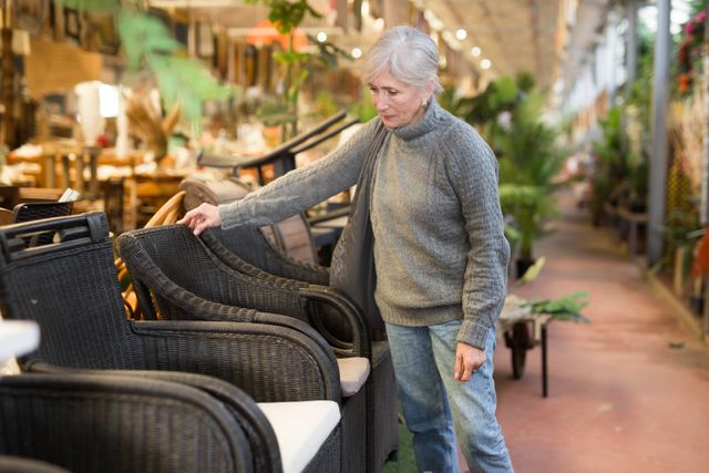 Side view of a woman examining an outdoor chair in an outdoor furniture store