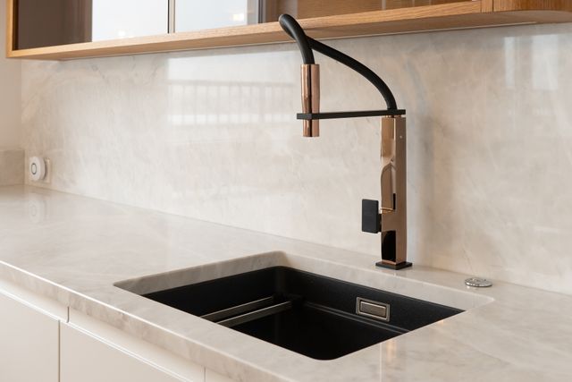 Close view of a modern wet bar space with a luxury matte black wet bar sink and black and bronze kitchen faucet
