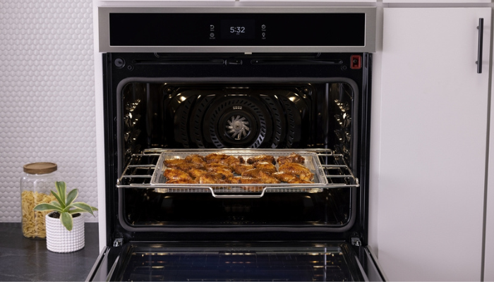 man removing air fried wings from a Frigidaire oven with air-fry technology