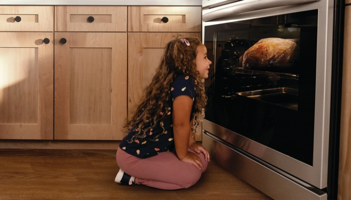 little girl eagerly waiting for food cooking in a Frigidaire oven