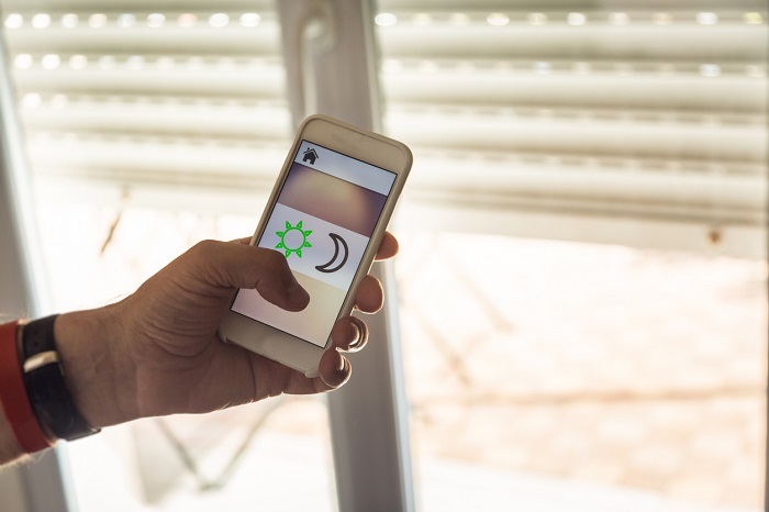 Man controlling blinds with app on his phone.