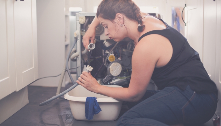 Woman inspecting the drainage issues on her dishwasher
