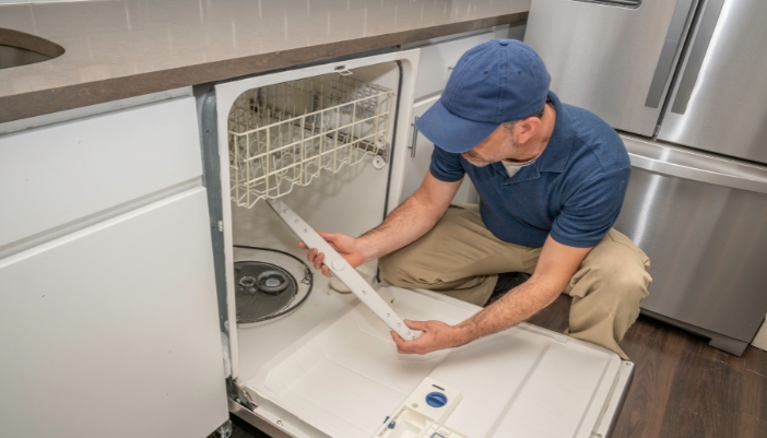 Appliance service tech checking the spray arms of a dishwasher