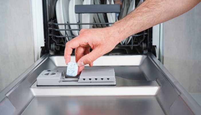 Closeup of someone using dishwasher pods