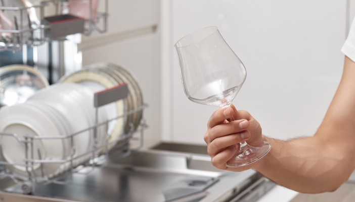 Closeup of someone holding up a sparkling wine glass out of the dishwasher
