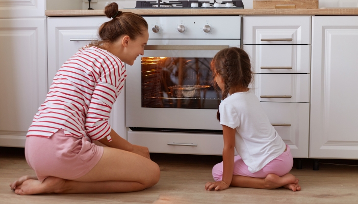 Mother and daughter checking the oven while it cooks something