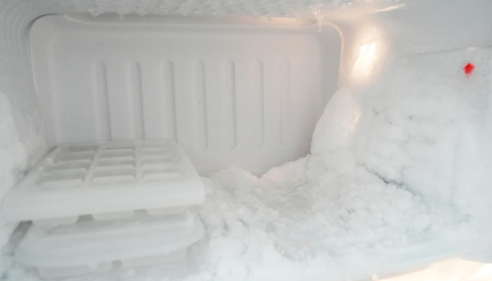 Interior shot of a freezer with lots of frost buildup and ice cube trays