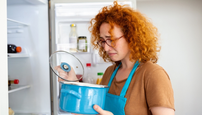 Woman throwing out expired food in a pot that smells bad