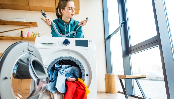 Closeup of someone holding the washer plug and the disconnected hose