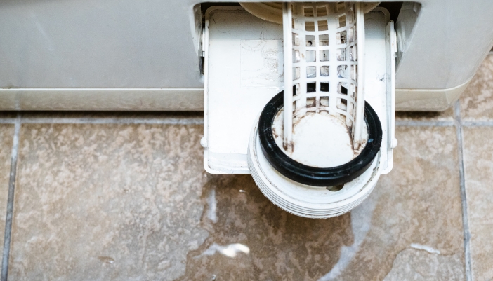 Closeup of a clean washer machine filter with spilled water around it