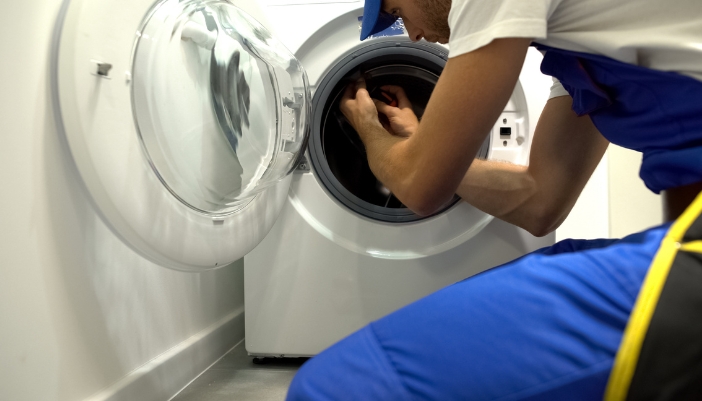 An appliance technician checking out the problems in a washer